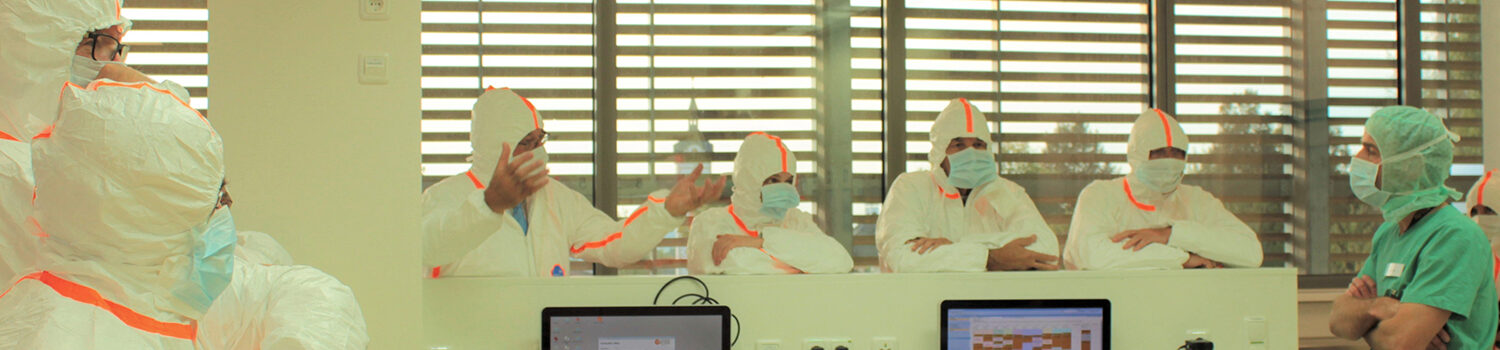 Bild mehrere Mediziner/innen in Schutzanzügen und Maske in Klinik. Dies ist ein Symbolbild für die Rubrik Corona-Infos.